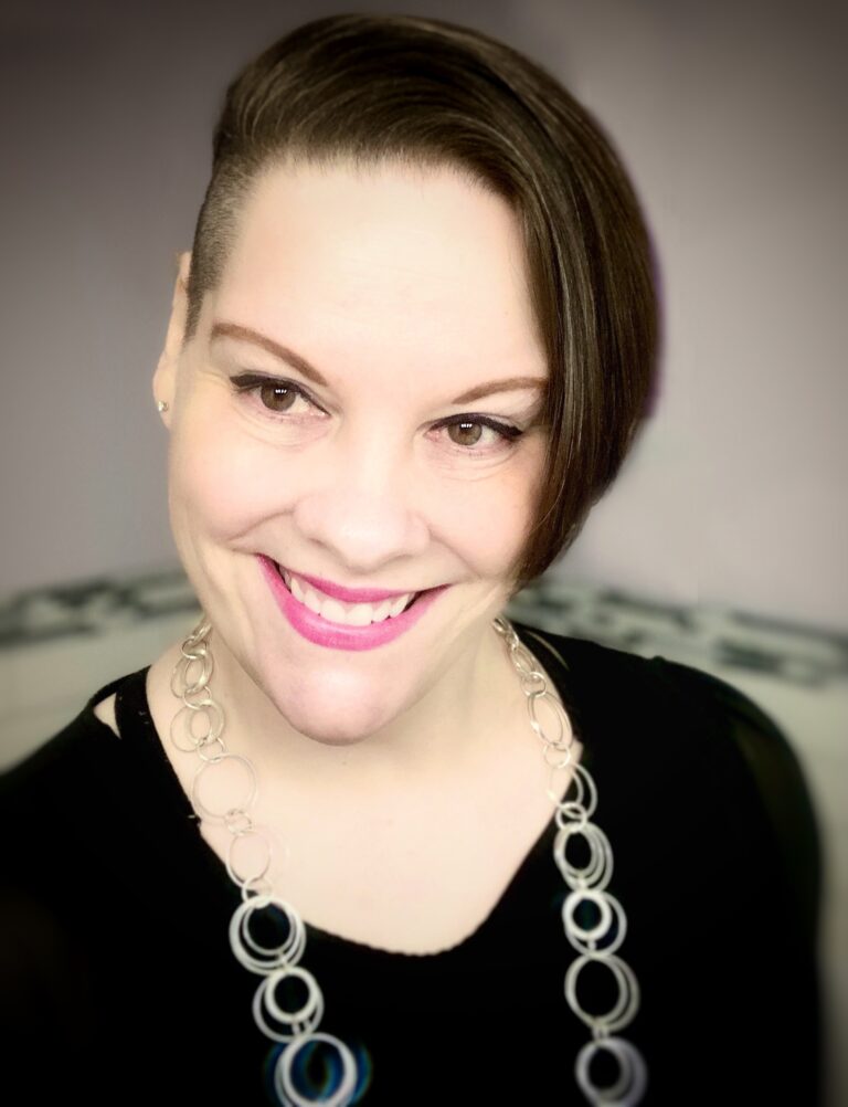 woman with short brown hair and a silver necklace, smiling